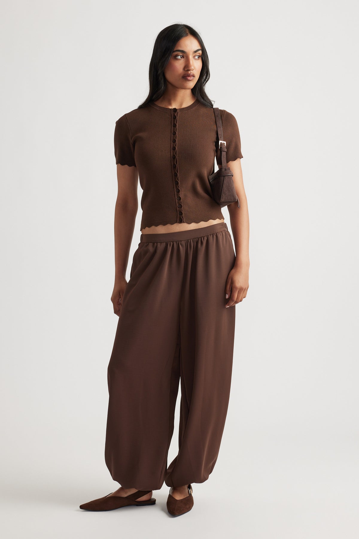 Woman wearing Maya Scallop Trim Button Top in warm coffee brown with delicate scalloped edges, styled with matching relaxed pants by DECJUBA