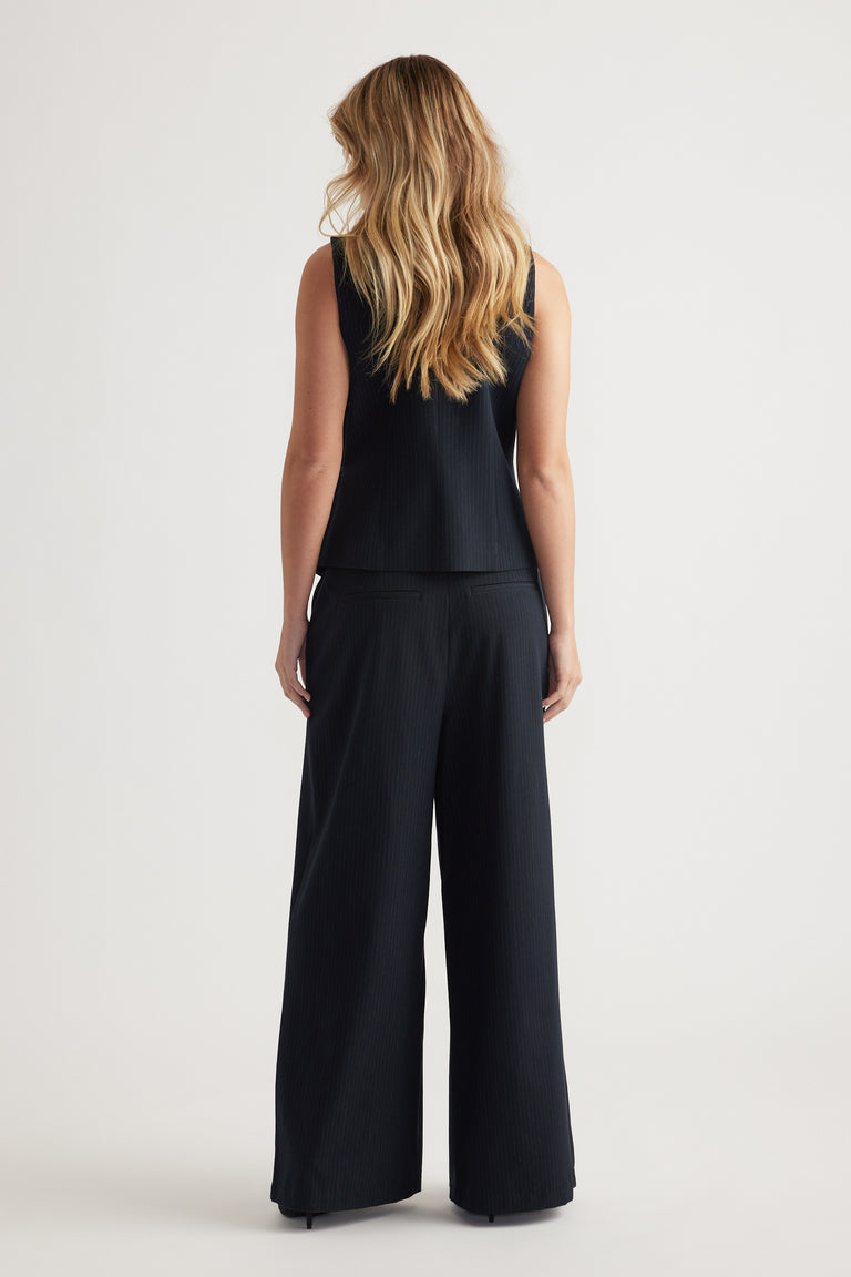 Woman seen from behind wearing a black ribbed side tie vest paired with wide-leg coordinating pants against a plain background