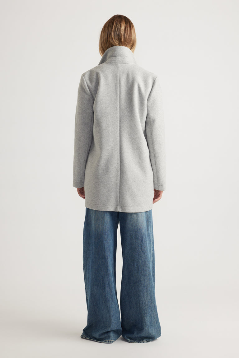 Woman wearing a light grey mid length coat paired with wide-leg blue denim jeans for a relaxed look