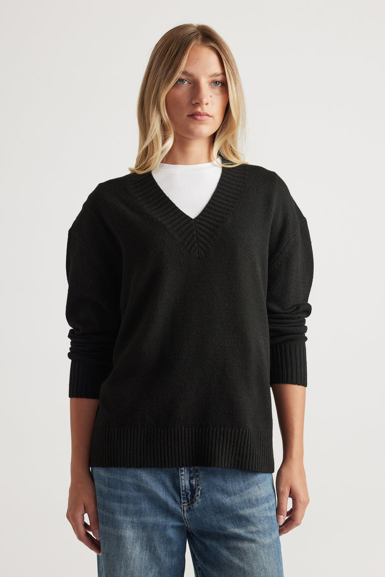 Woman wearing black V Neck Knit Jumper layered over white top with relaxed blue denim jeans by Decjuba Australian brand