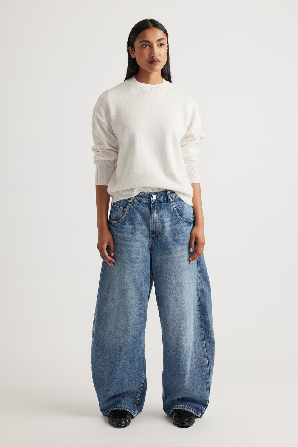 Woman wearing Crew Neck Knit Jumper in soft cream knitwear styled with relaxed wide-leg denim jeans by Decjuba Australian brand