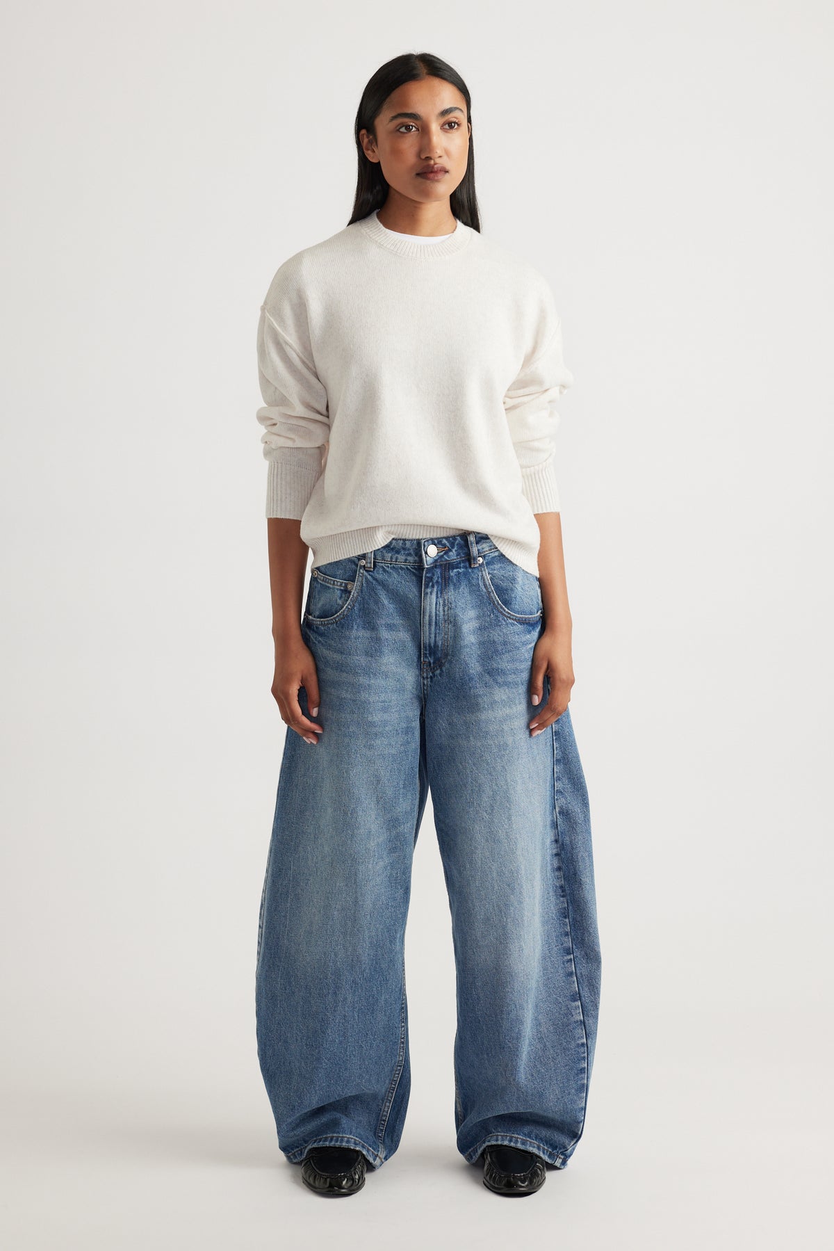Woman wearing Crew Neck Knit Jumper in soft cream knitwear styled with relaxed wide-leg denim jeans by Decjuba Australian brand