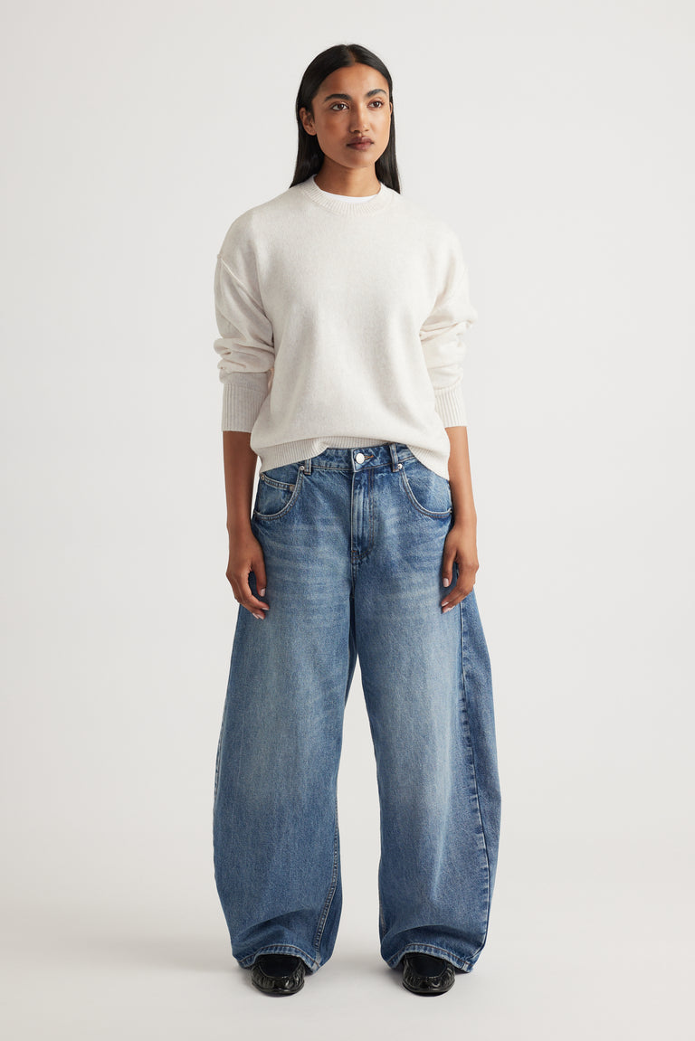 Woman wearing Crew Neck Knit Jumper in soft cream knitwear styled with relaxed wide-leg denim jeans by Decjuba Australian brand
