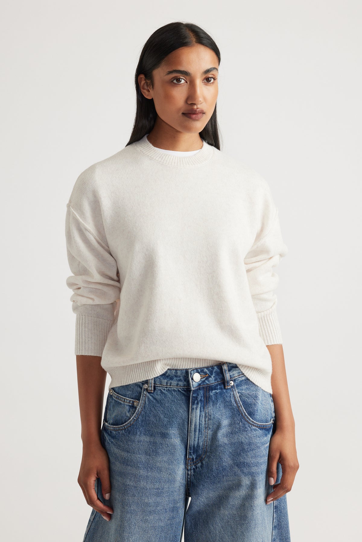 Woman wearing Crew Neck Knit Jumper in soft cream knitwear with relaxed fit, styled with casual blue denim jeans by Decjuba Australian brand