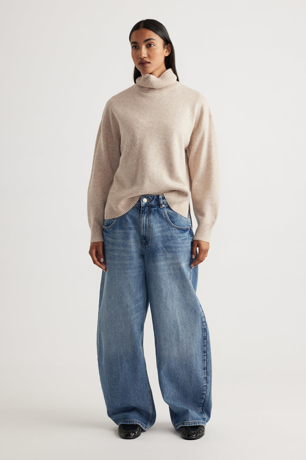 Woman modeling Roll Neck Knit Jumper in soft beige knitwear paired with relaxed wide-leg denim jeans by Decjuba Australian brand