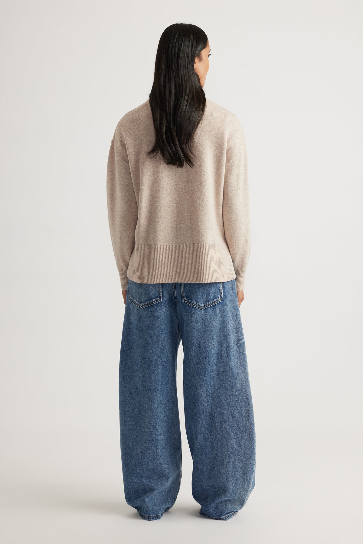 Back view of Roll Neck Knit Jumper in soft beige knitwear styled with relaxed wide-leg denim jeans by Decjuba Australian brand