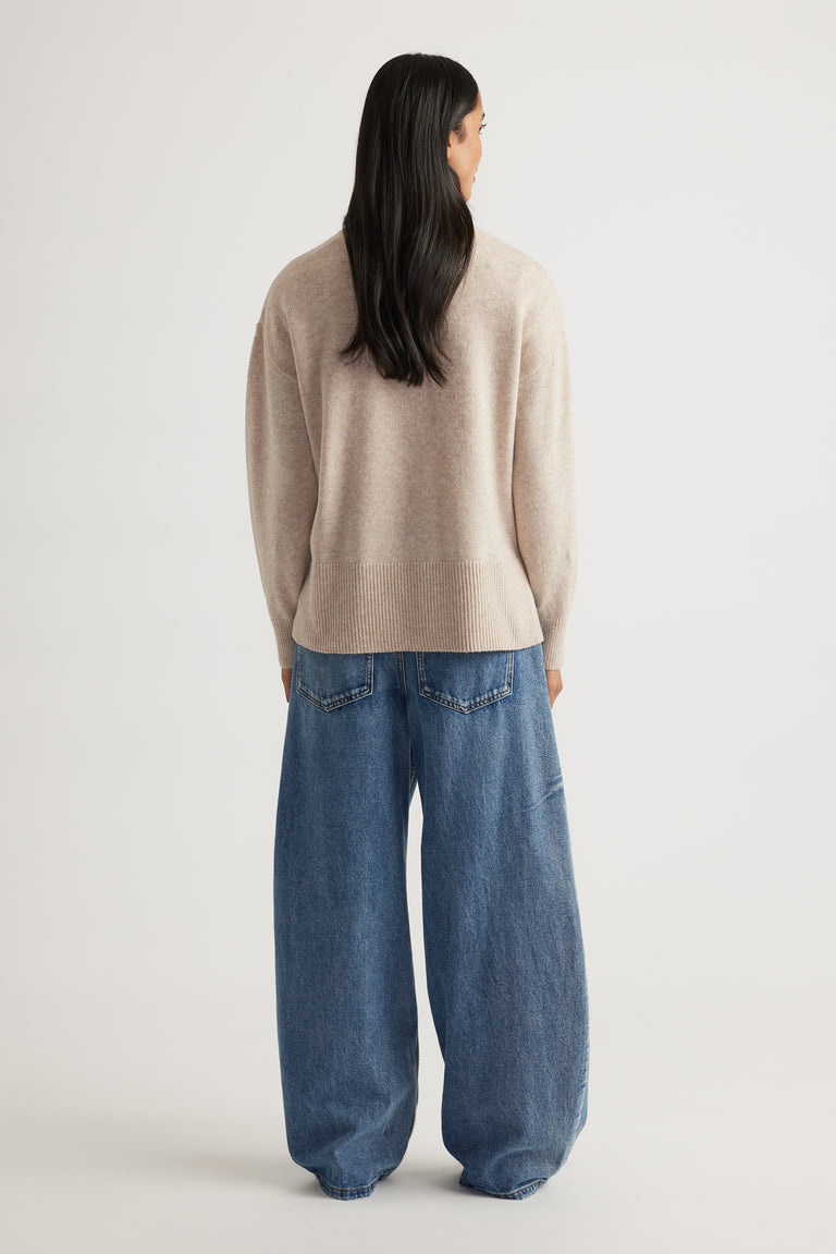 Back view of Roll Neck Knit Jumper in soft beige knitwear styled with relaxed wide-leg denim jeans by Decjuba Australian brand