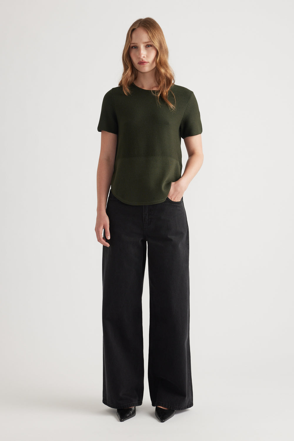 Woman wearing an olive green knit short sleeve top paired with wide-leg black jeans for a relaxed look