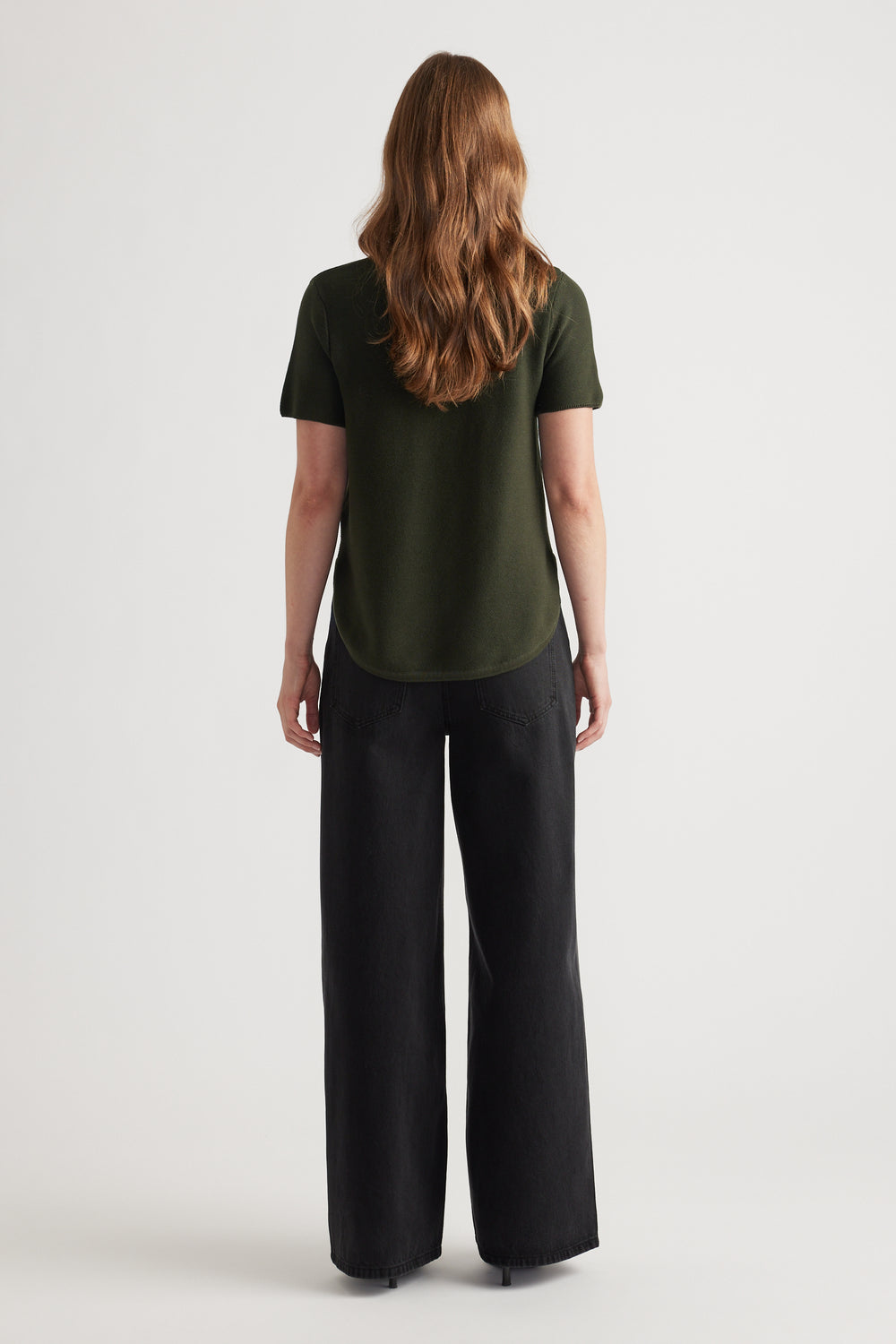 Woman seen from behind wearing a forest green short sleeve knit top paired with wide-leg black pants