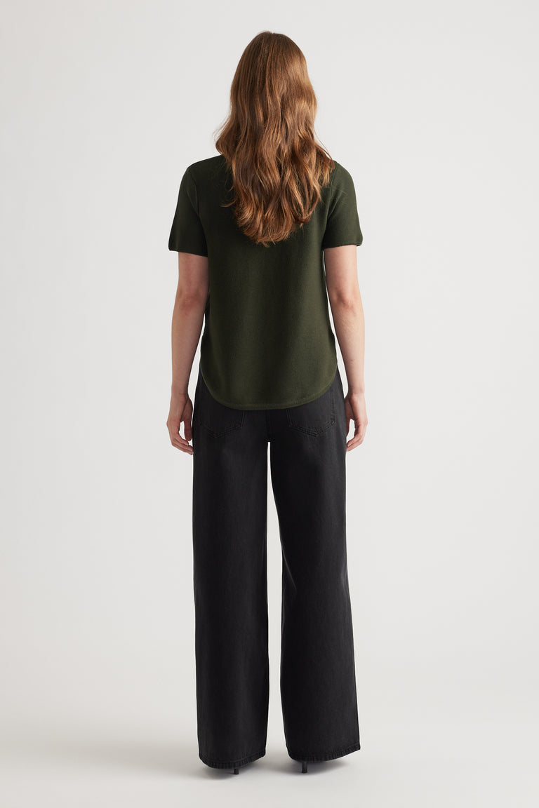 Woman seen from behind wearing a forest green short sleeve knit top paired with wide-leg black pants