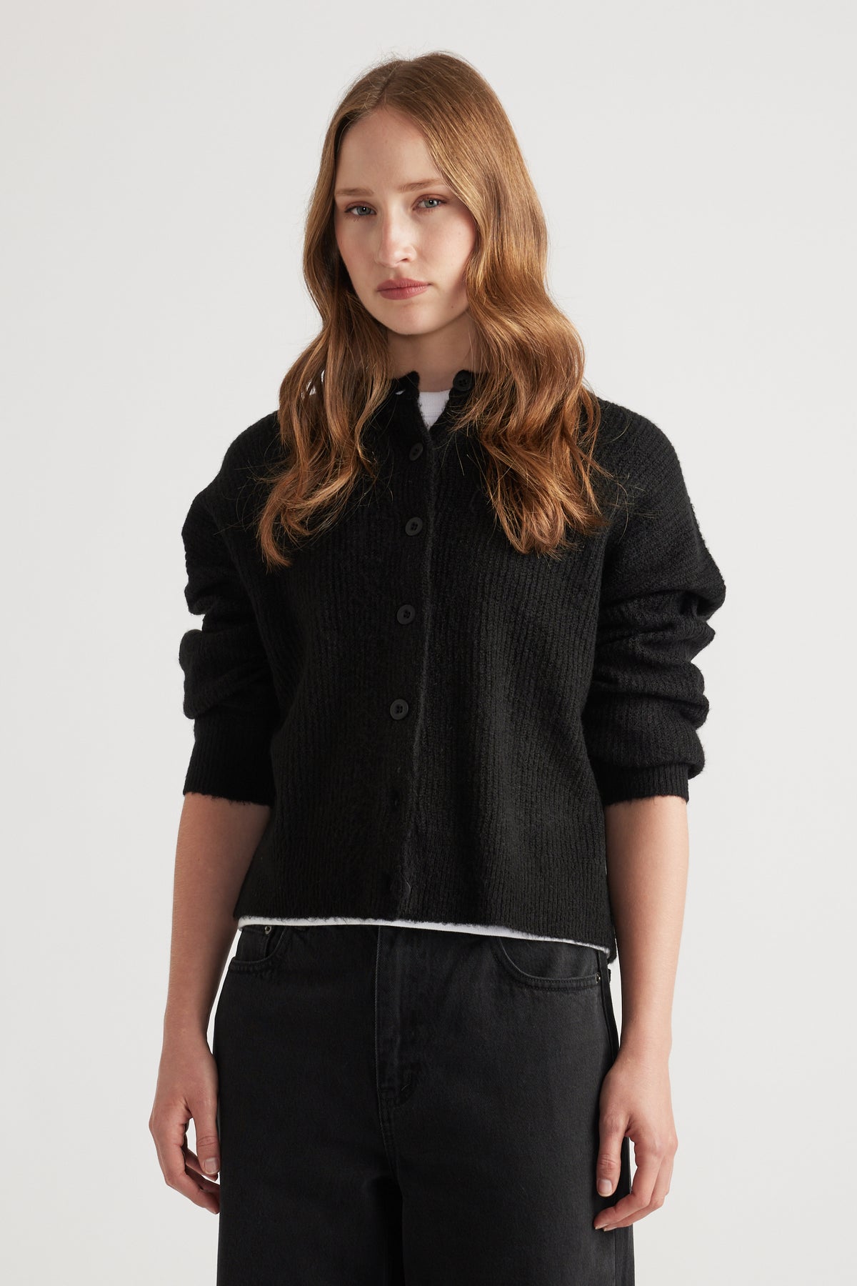Woman wearing a cozy black knit cardigan with a relaxed fit, styled with black high-waisted pants for a casual look