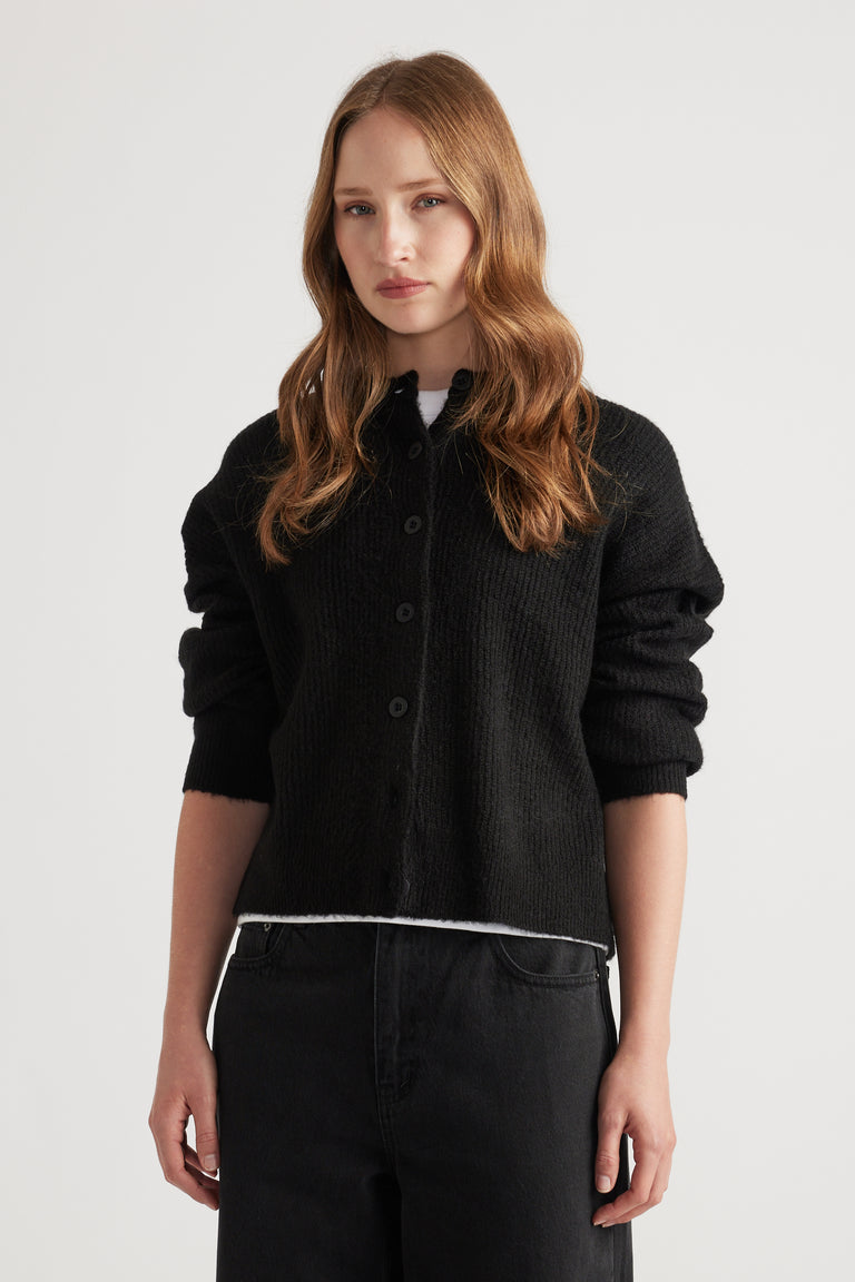 Woman wearing a cozy black knit cardigan with a relaxed fit, styled with black high-waisted pants for a casual look