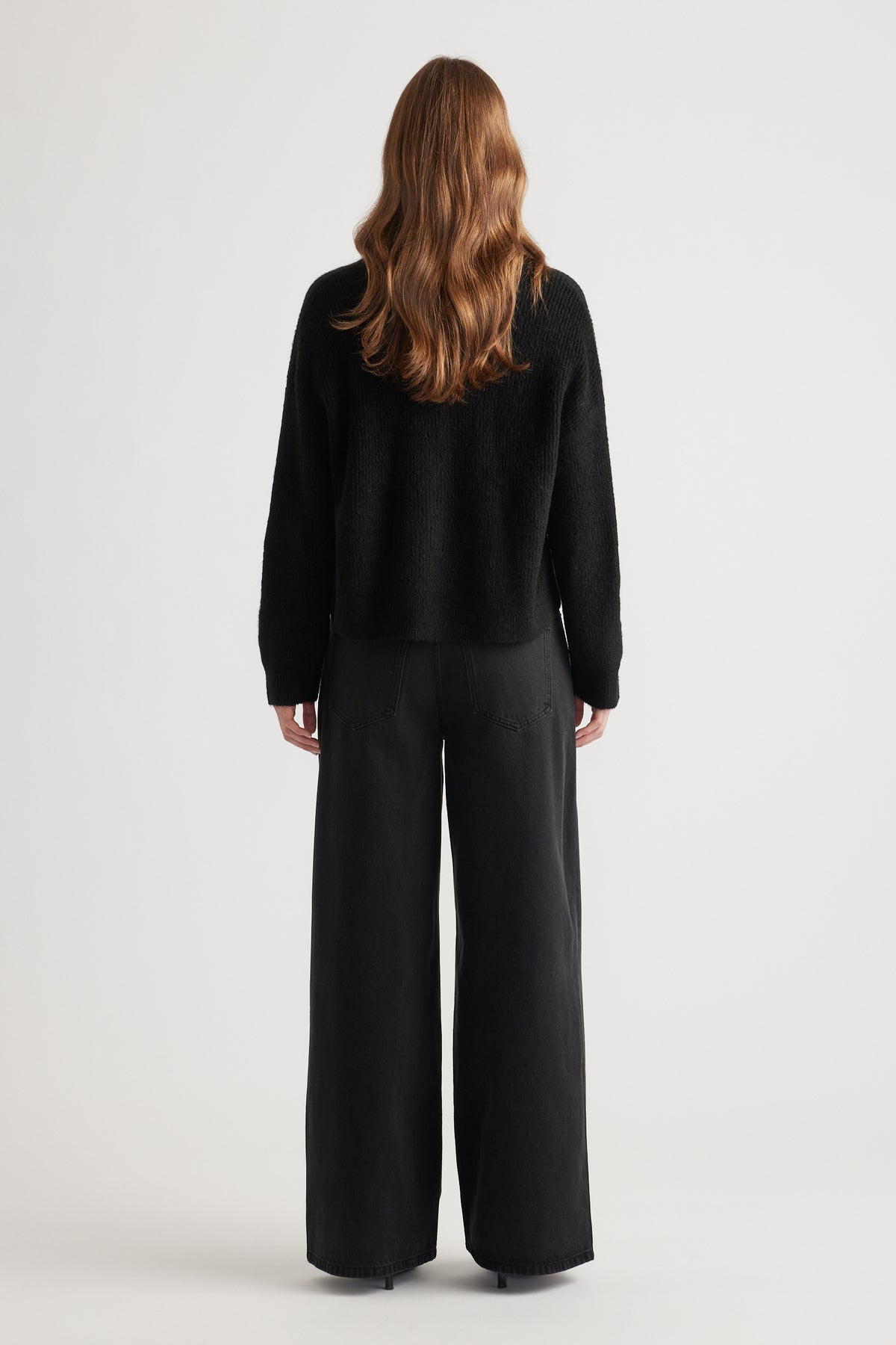 Woman wearing a cozy black knit cardigan paired with relaxed wide-leg black pants for a minimalist look