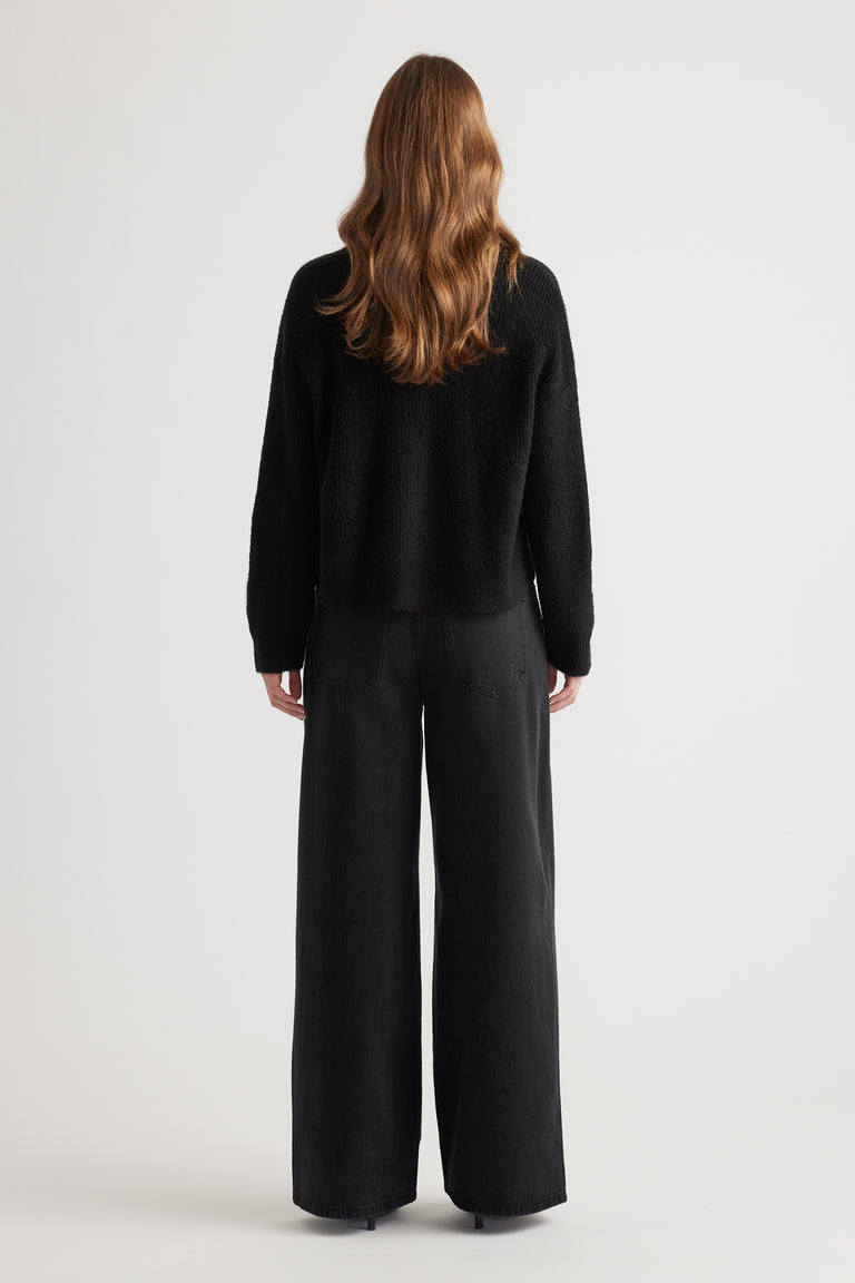 Woman wearing a cozy black knit cardigan paired with relaxed wide-leg black pants for a minimalist look