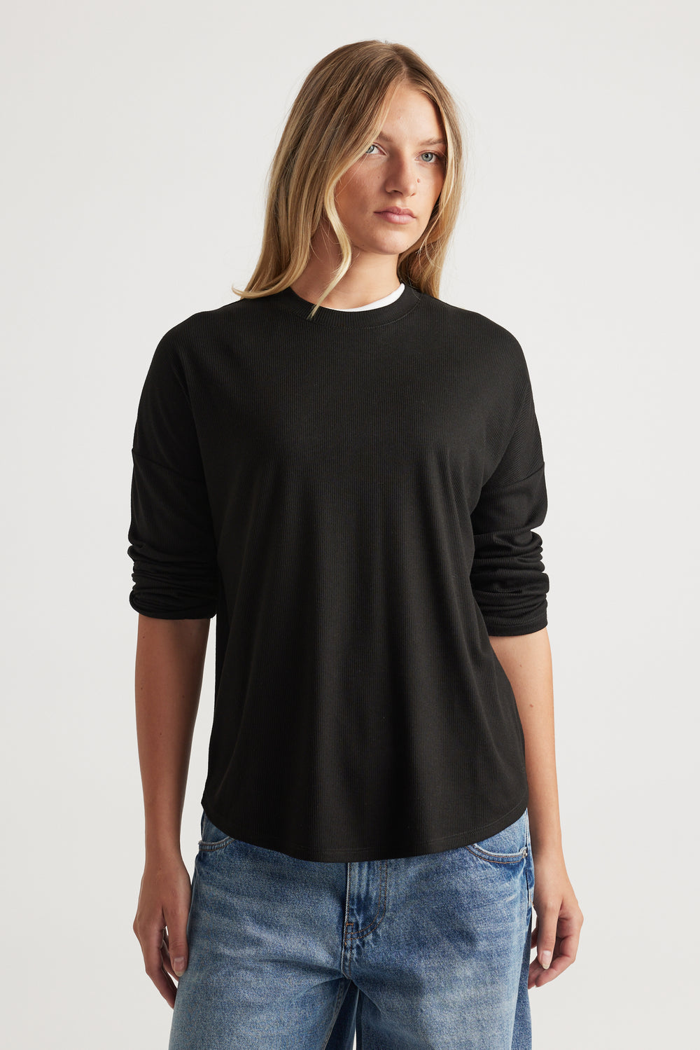 Woman wearing a relaxed-fit black long sleeve rib top paired with light wash blue jeans for a casual look