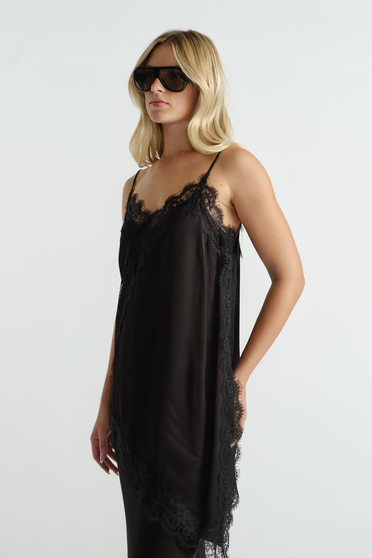 Woman wearing a black lace-trimmed slip dress with thin straps and oversized sunglasses for a chic look