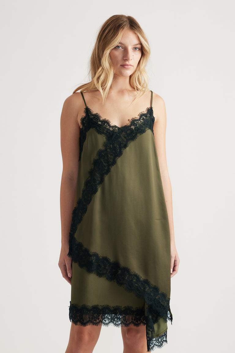 Woman wearing an olive green lace-trimmed slip dress with delicate straps and a relaxed fit.