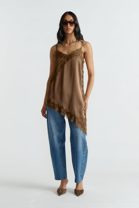 Woman wearing brown lace-trimmed tunic with adjustable straps paired with loose mid-blue denim jeans and pointed flats