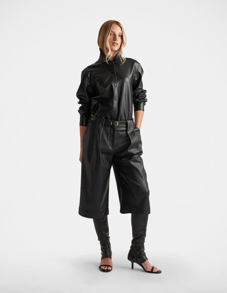 Woman wearing Jemma Faux Leather Shirt in black with long sleeves, button front, paired with matching culottes and heels by DECJUBA