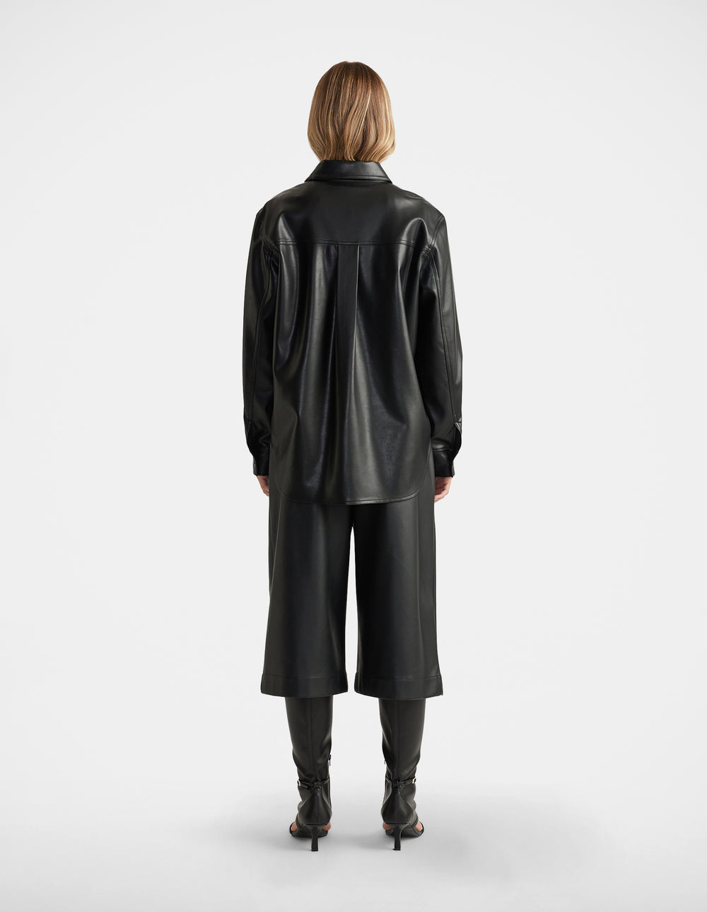 Woman seen from behind wearing Jemma Faux Leather Shirt in black with relaxed fit, paired with matching wide-leg culottes by DECJUBA