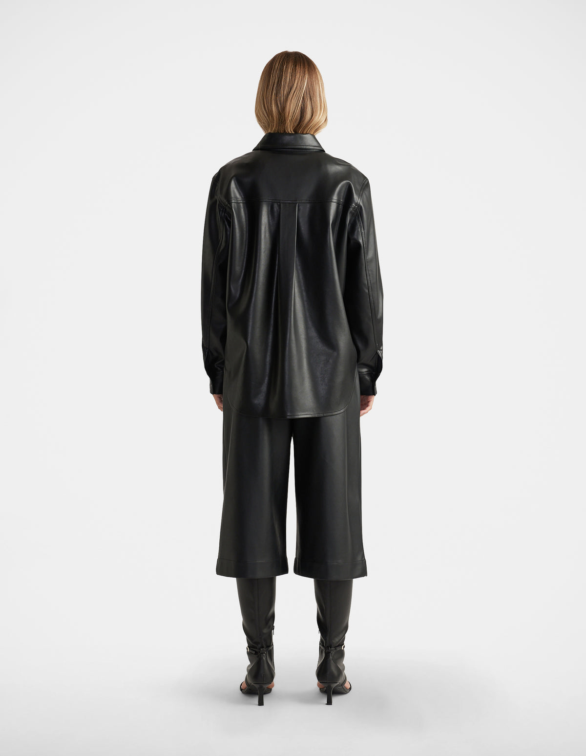 Woman seen from behind wearing Jemma Faux Leather Shirt in black with relaxed fit, paired with matching wide-leg culottes by DECJUBA
