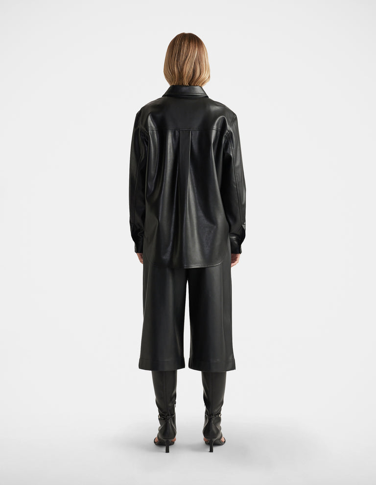 Woman seen from behind wearing Jemma Faux Leather Shirt in black with relaxed fit, paired with matching wide-leg culottes by DECJUBA