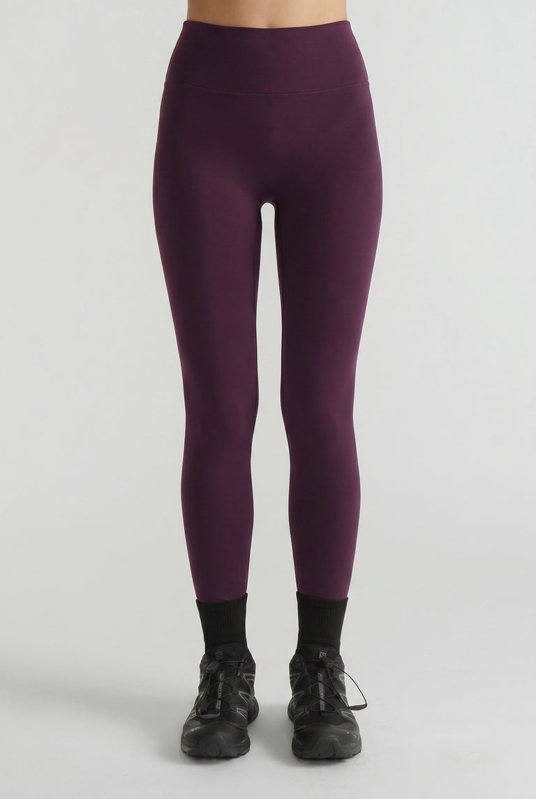 High-rise plum leggings with a smooth, streamlined fit paired with black athletic shoes for a sleek sporty look
