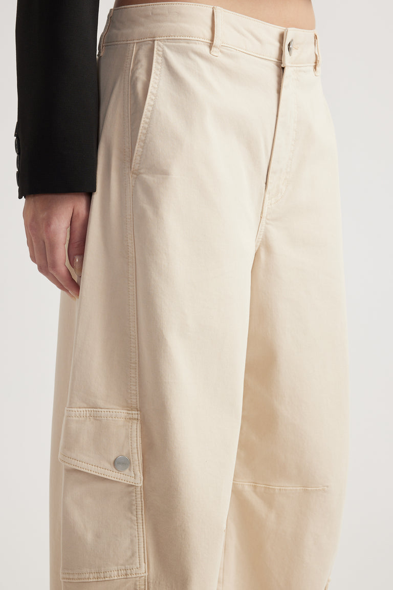 Woman wearing cream barrel leg cargo pants with flap cargo pockets and a black blazer