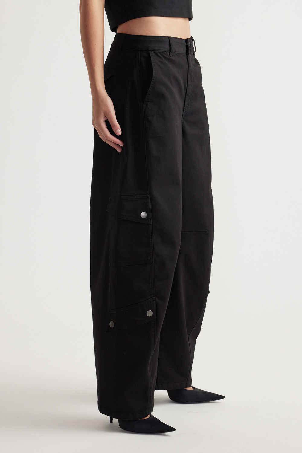 Woman wearing relaxed black wide-leg cargo pants with flap pockets and subtle metal snap details