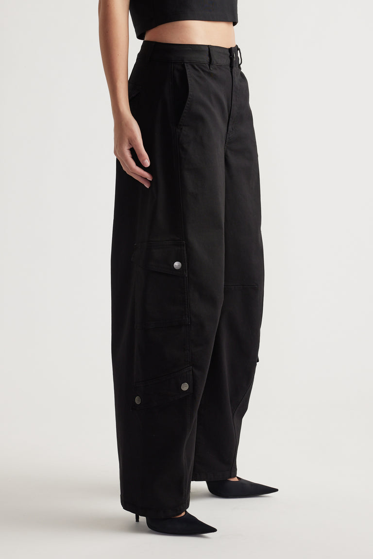 Woman wearing relaxed black wide-leg cargo pants with flap pockets and subtle metal snap details