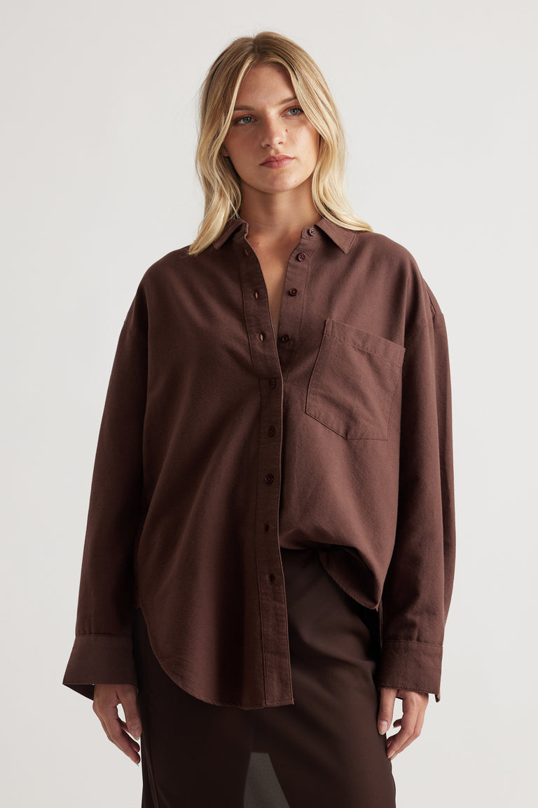 Blonde woman wearing a relaxed fit deep brown oversized shirt with a front chest pocket and button closure