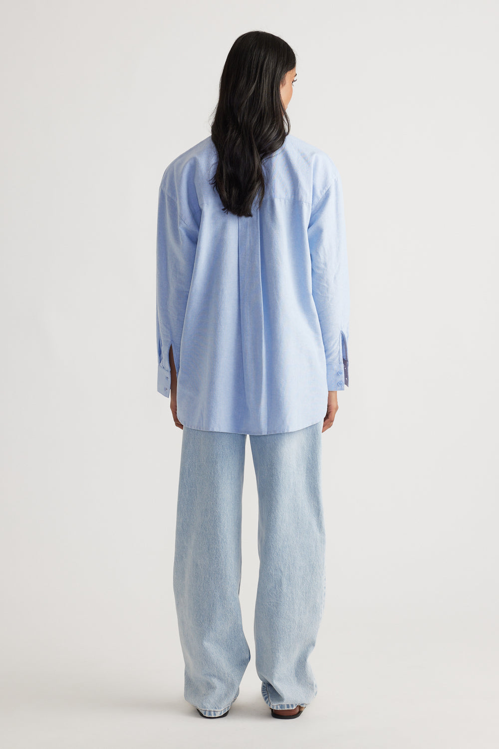 Back view of a light blue oversized shirt paired with relaxed wide-leg light-wash denim jeans for a casual look