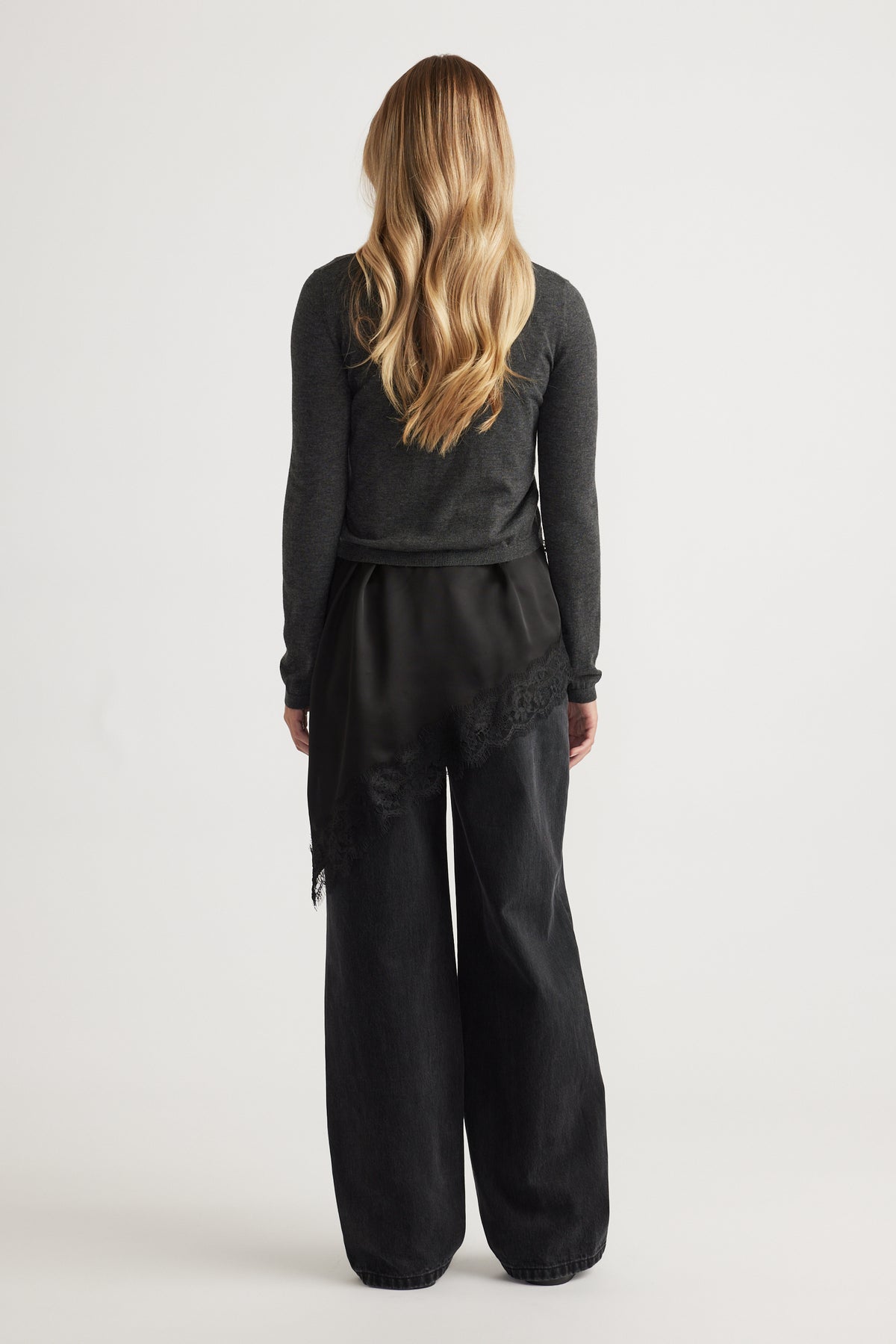 Woman seen from behind wearing Bella Button Through Cardigan in dark grey knit paired with wide-leg black pants by DECJUBA