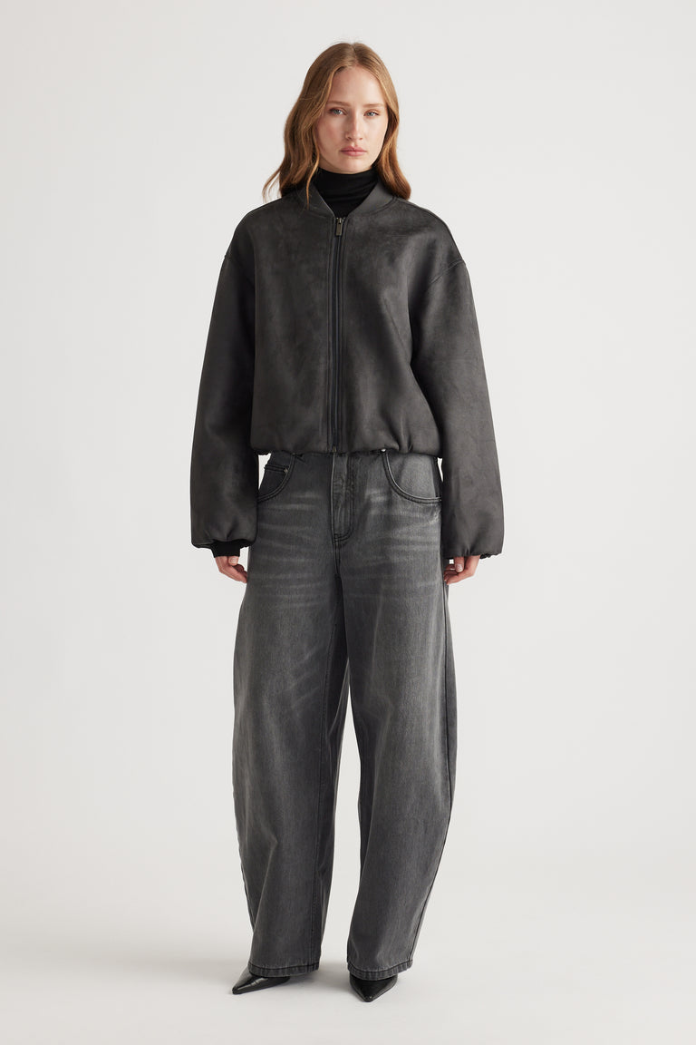 Woman wearing Eden Faux Suede Bomber Jacket in charcoal paired with wide-leg dark denim jeans and black turtleneck.