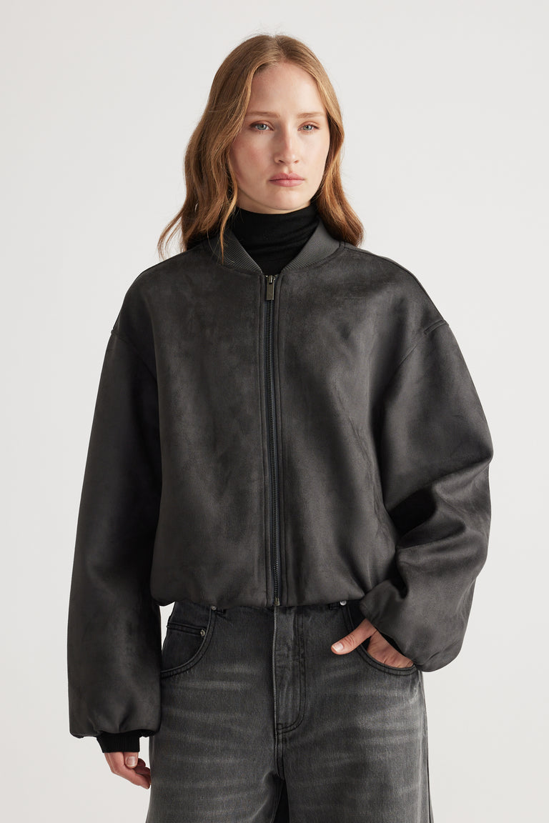 Woman wearing a charcoal Eden Faux Suede Bomber Jacket styled with black turtleneck and washed black jeans for a modern look