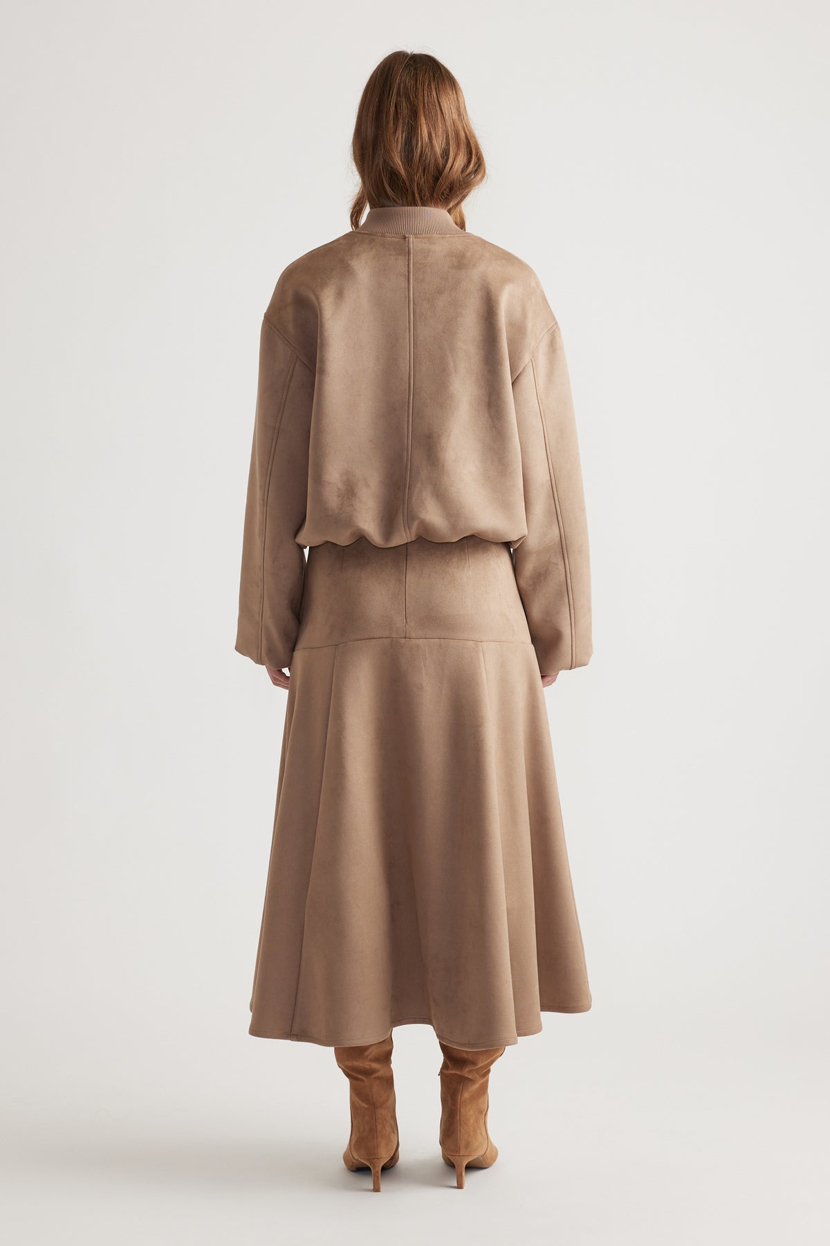 Back view of a dove grey faux suede midi skirt styled with a matching jacket and tan suede boots