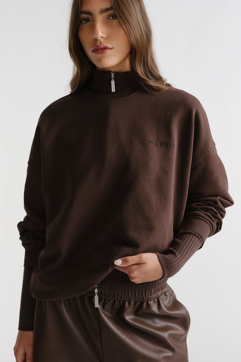 Woman wearing D-Luxe Washed Terry Sweat in rich walnut brown with zip neck and ribbed cuffs for cozy, stylish layering