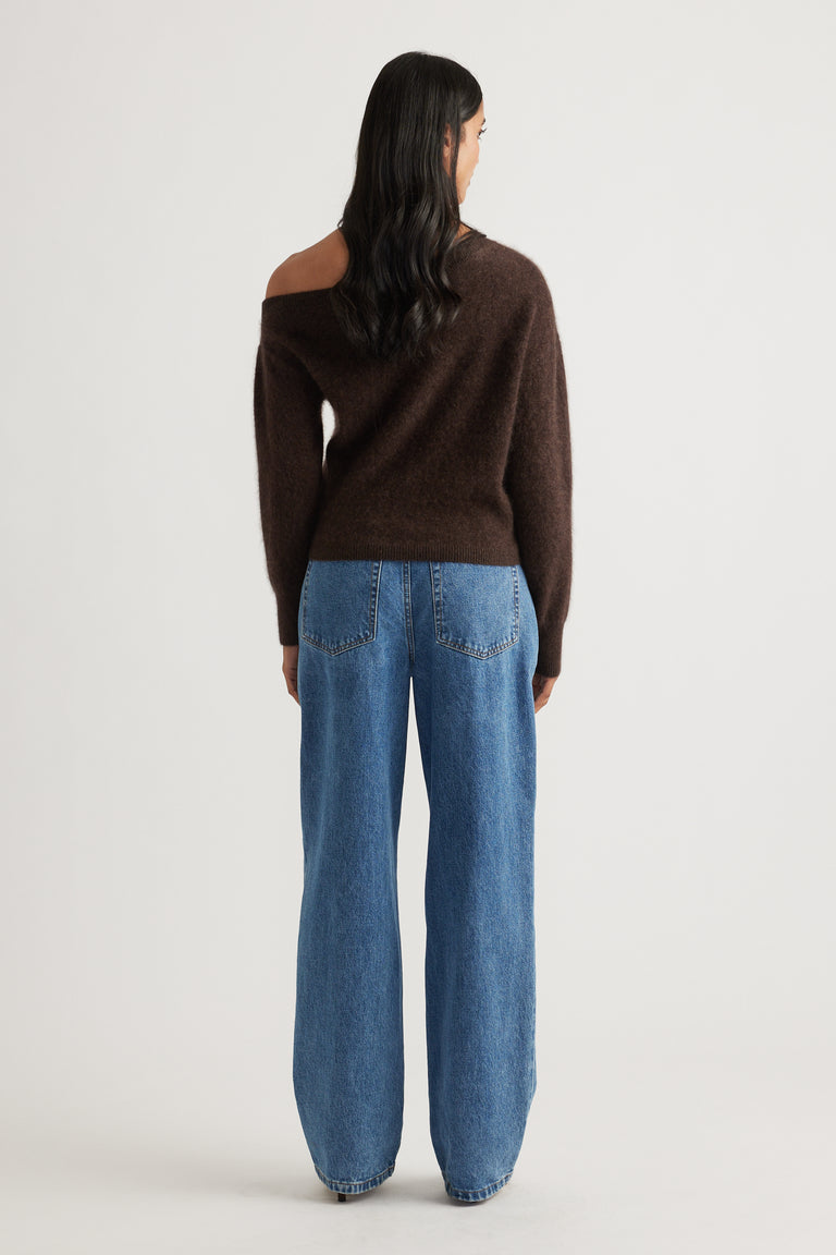 Back view of woman wearing a soft chocolate brown wool jumper with drop shoulder paired with relaxed blue denim jeans