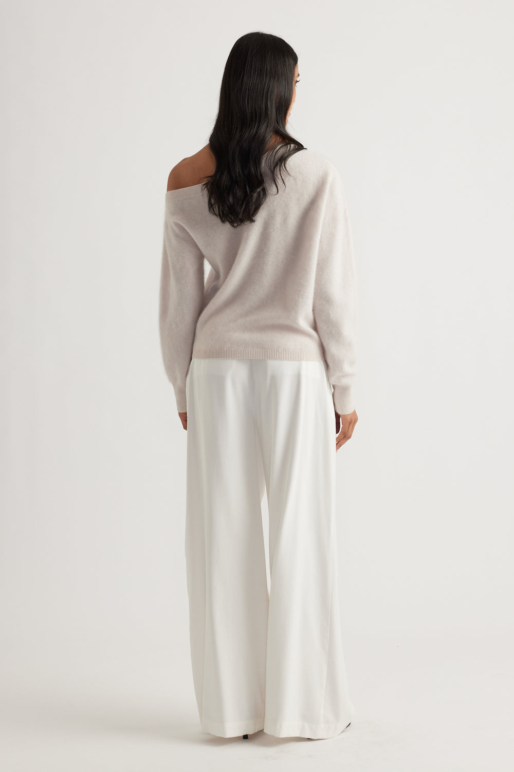 Back view of woman wearing a soft sand-colored wool jumper with wide-leg white trousers for an elegant look