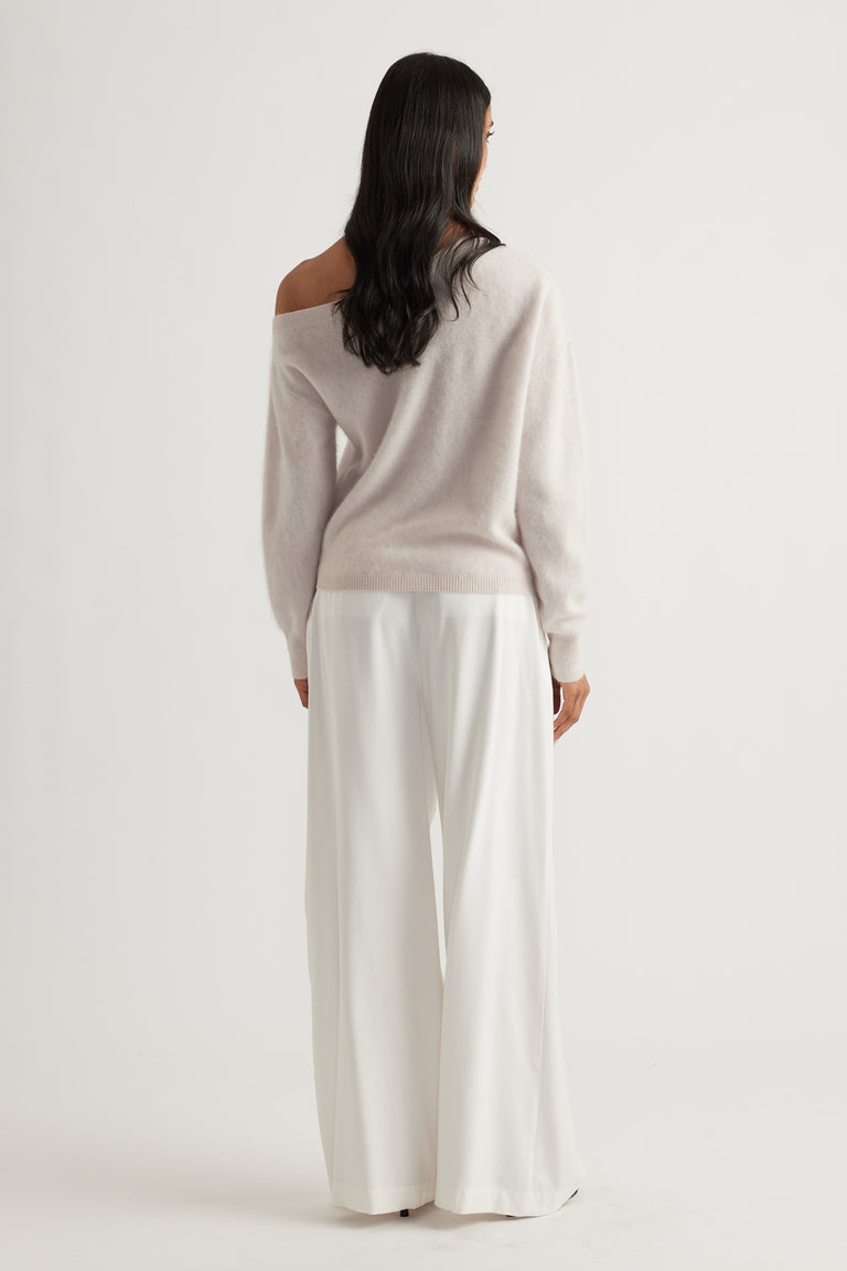 Back view of woman wearing a soft sand-colored wool jumper with wide-leg white trousers for an elegant look