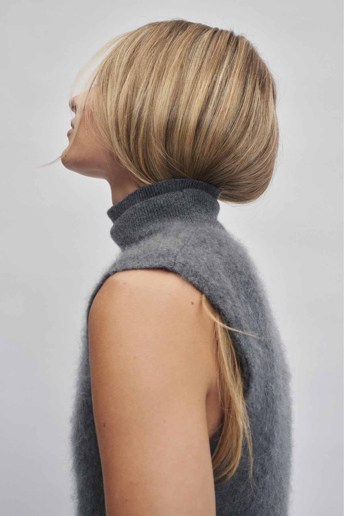 Soft charcoal sleeveless wool knit vest with a high neck, styled for a cozy, timeless layered look