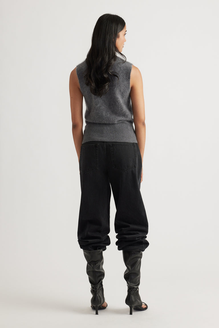 Back view of woman wearing a charcoal sleeveless wool knit vest paired with black relaxed-fit pants and heeled boots