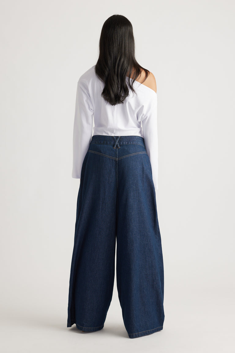 Woman shown from behind wearing dark wide-leg denim jeans paired with an off-shoulder white top