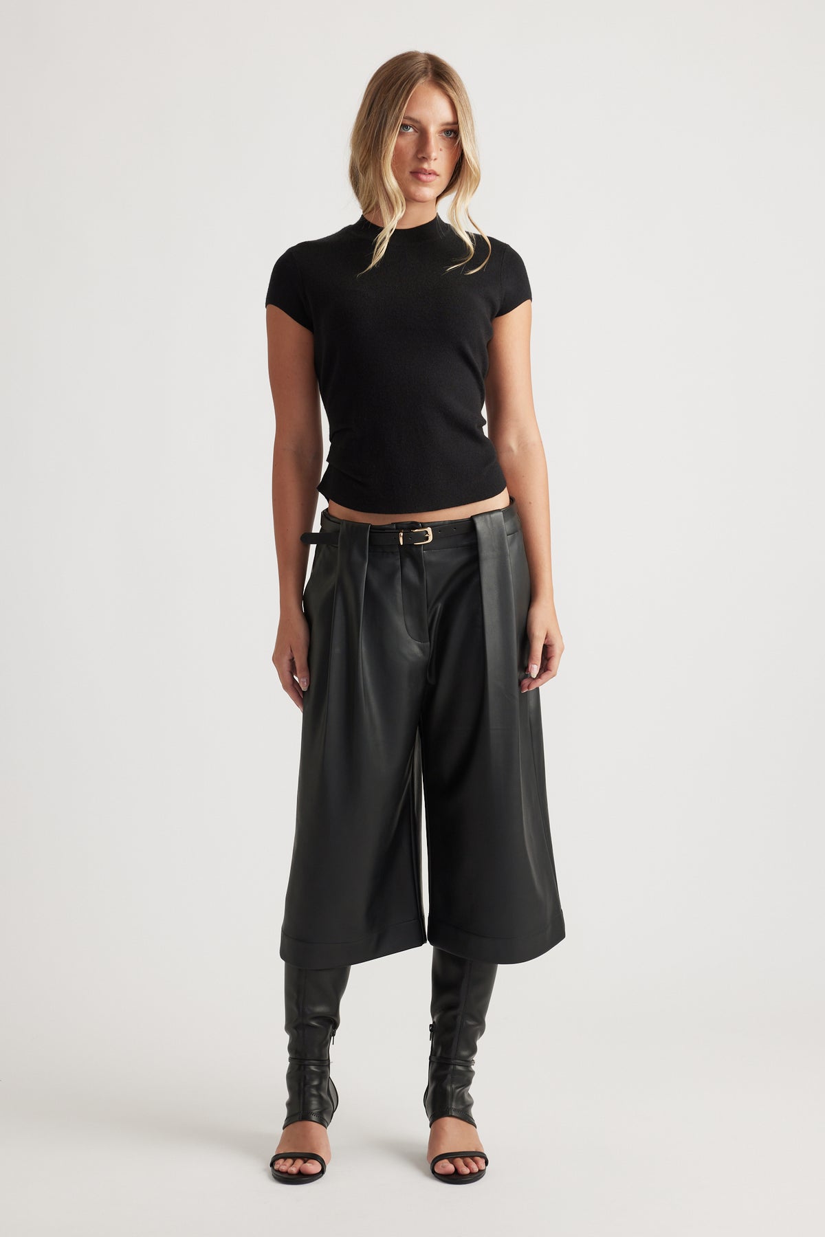 Woman wearing Lily Pleat Detail Knit Tee in black, styled with wide-leg cropped pants and heeled sandals by DECJUBA