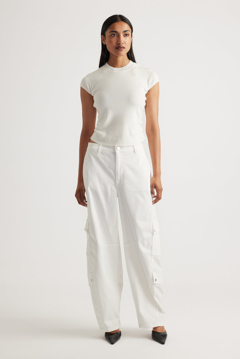 Woman wearing Lily Pleat Detail Knit Tee in soft winter white styled with relaxed white cargo pants and black pointed shoes by DECJUBA