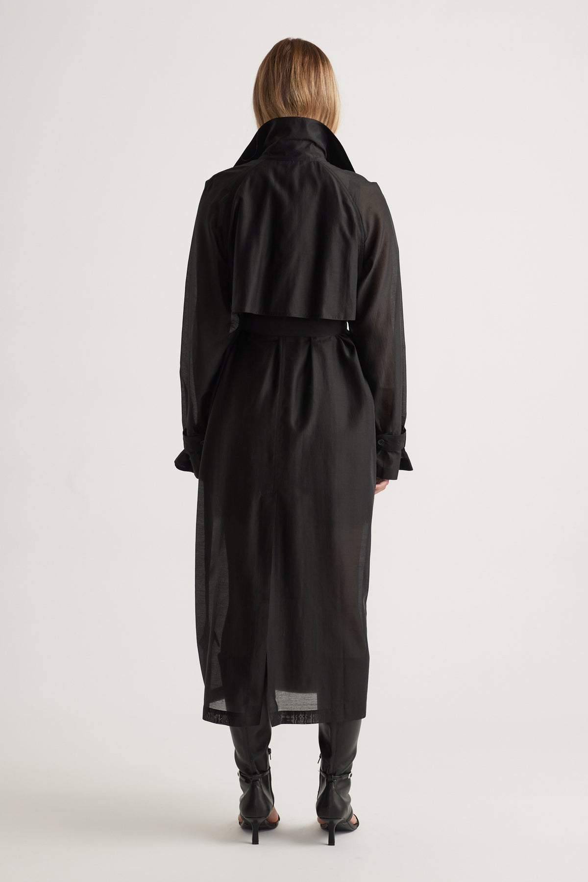 Woman wearing Briar Sheer Trench Coat in black with a lightweight, flowing design and belted waist by DECJUBA