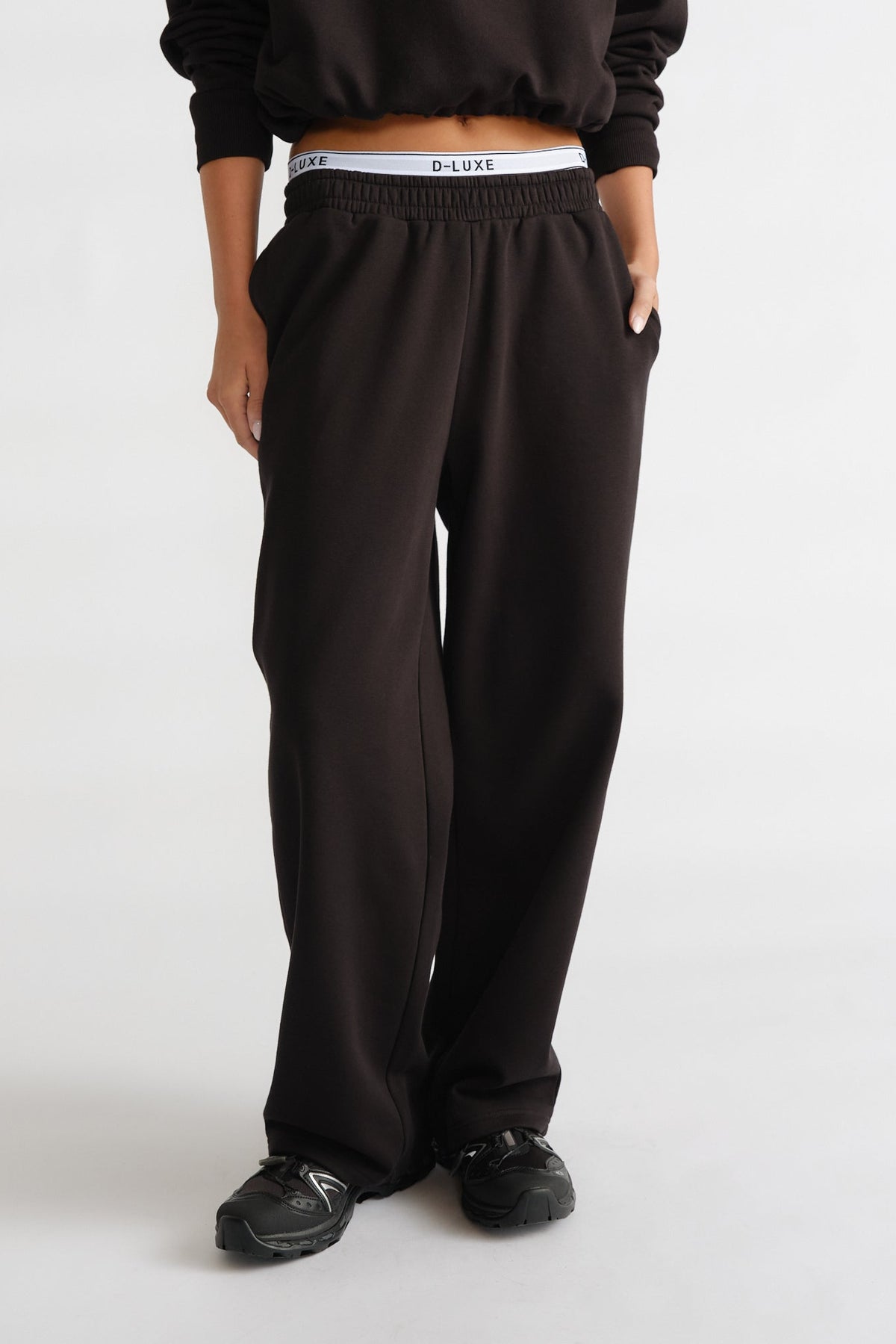 D-Luxe Logo Trackpant in black with a relaxed fit and elastic waistband, styled with casual sneakers by DECJUBA