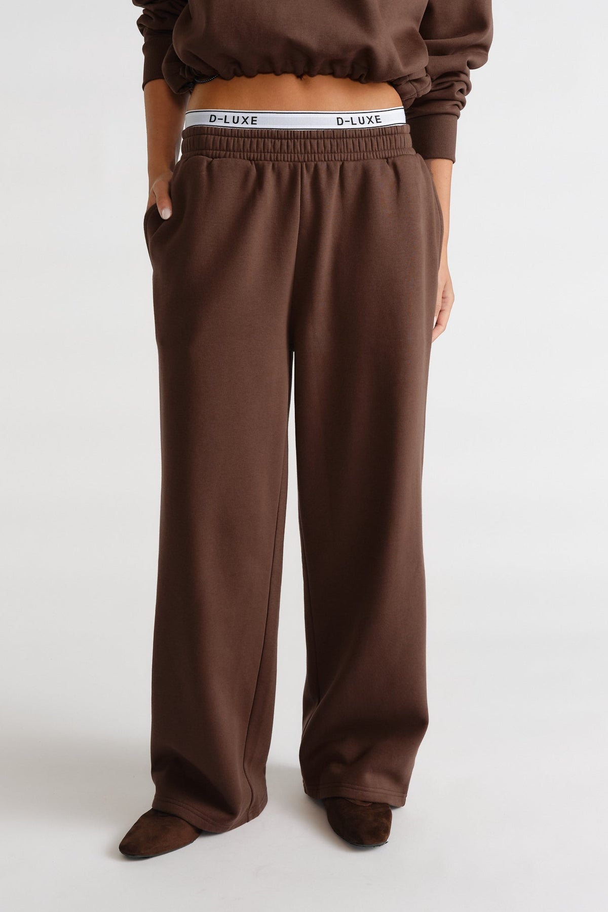 Relaxed-fit brown trackpants with elastic waist and logo waistband peeking above for casual, stylish comfort.