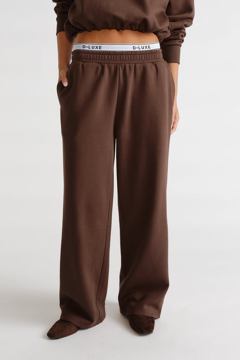 Relaxed-fit brown trackpants with elastic waist and logo waistband peeking above for casual, stylish comfort.