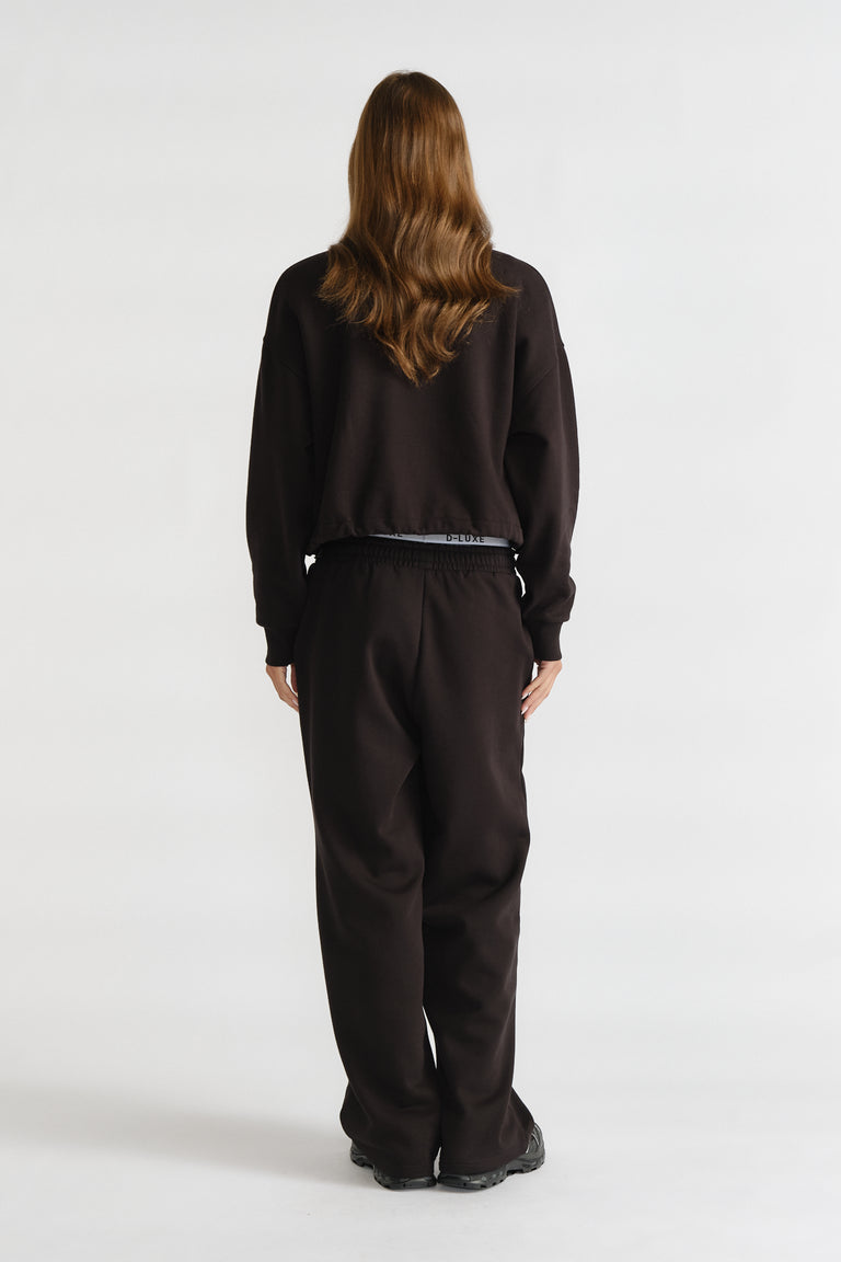 D-Luxe Logo Crop Sweat in black with a relaxed cropped fit, styled with matching black pants for a casual look by DECJUBA